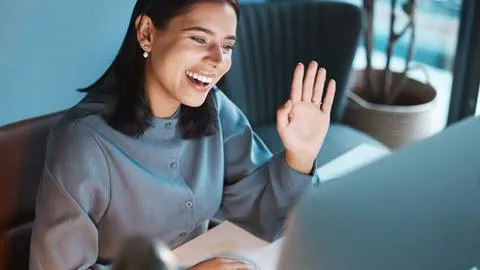 A woman in a business suit is waving her hand in front of a computer.