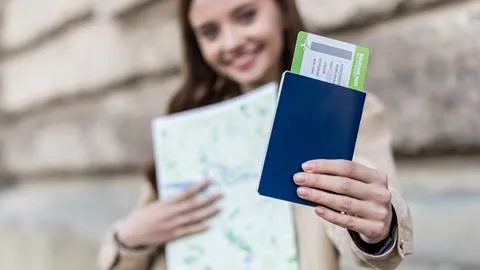A woman holding a passport and a map.