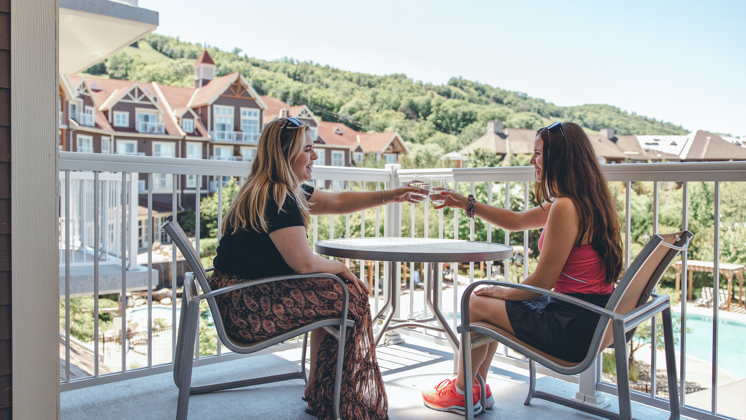 Pair of friends sitting on balcony of Westin Trillium House, Blue Mountain overlooking mountain and enjoying a glass of wine