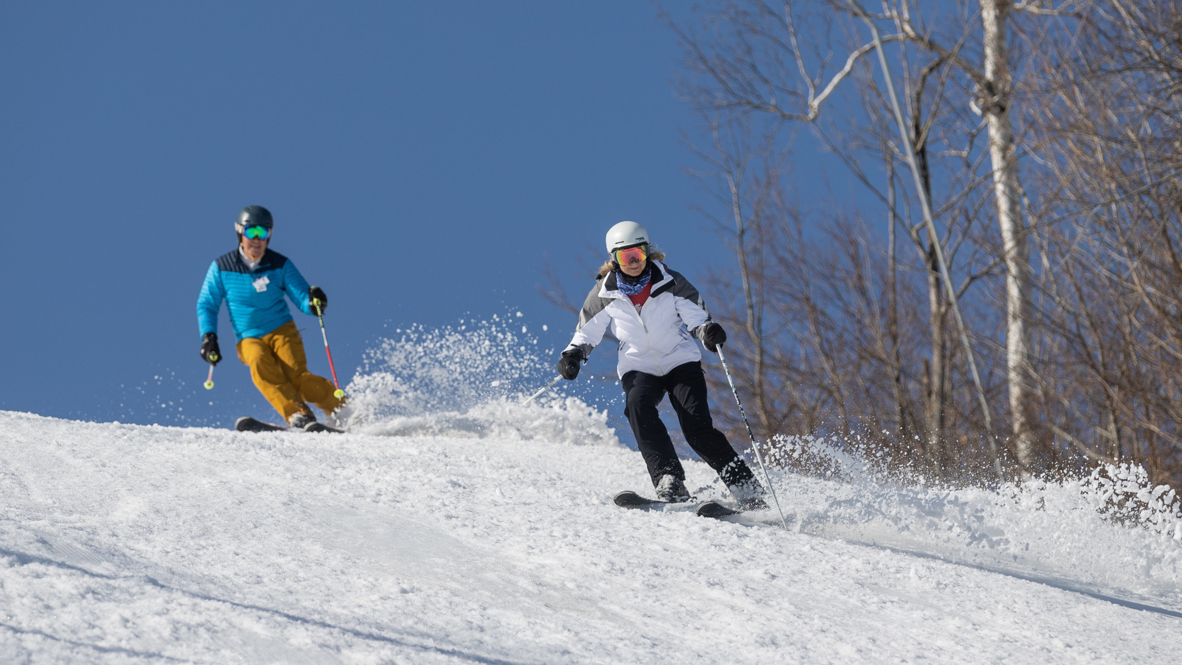 Two skiers in spring skiing down the hill at Blue Mountain