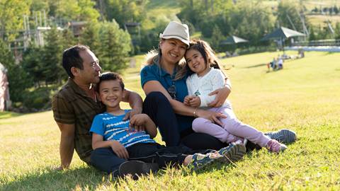 Family of four sitting on the grass enjoying the sun at Blue Mountain Resort