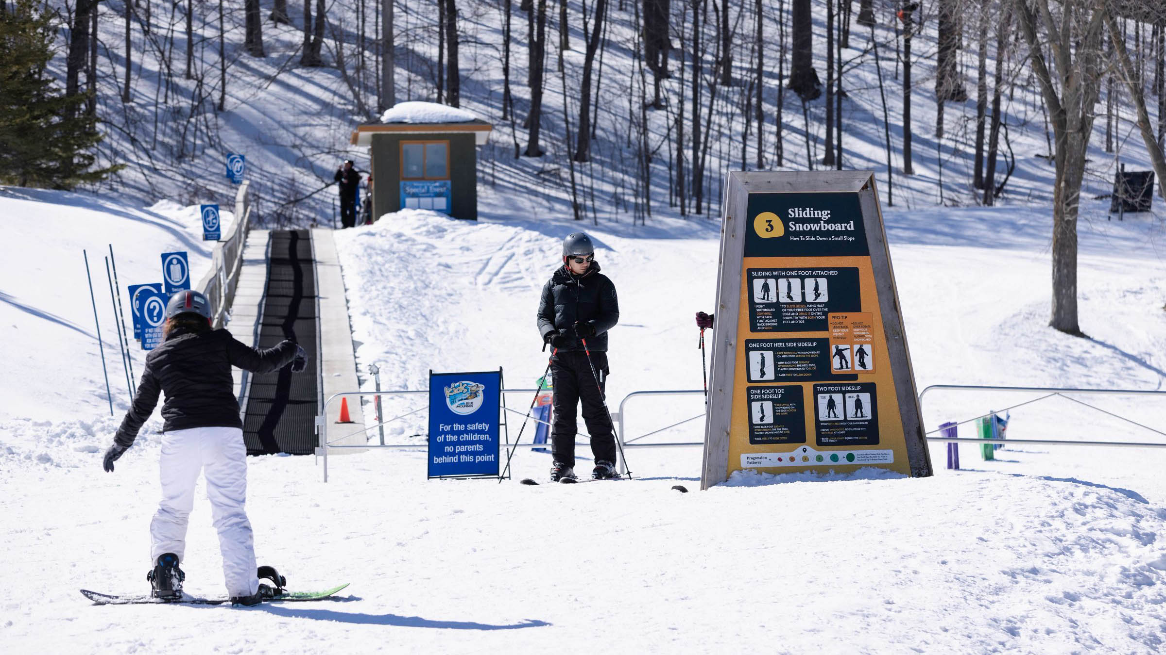 Snowboarder and skier on beginner trail learning how to ski and learning how to snowboard using the Snow How Self-Learn System