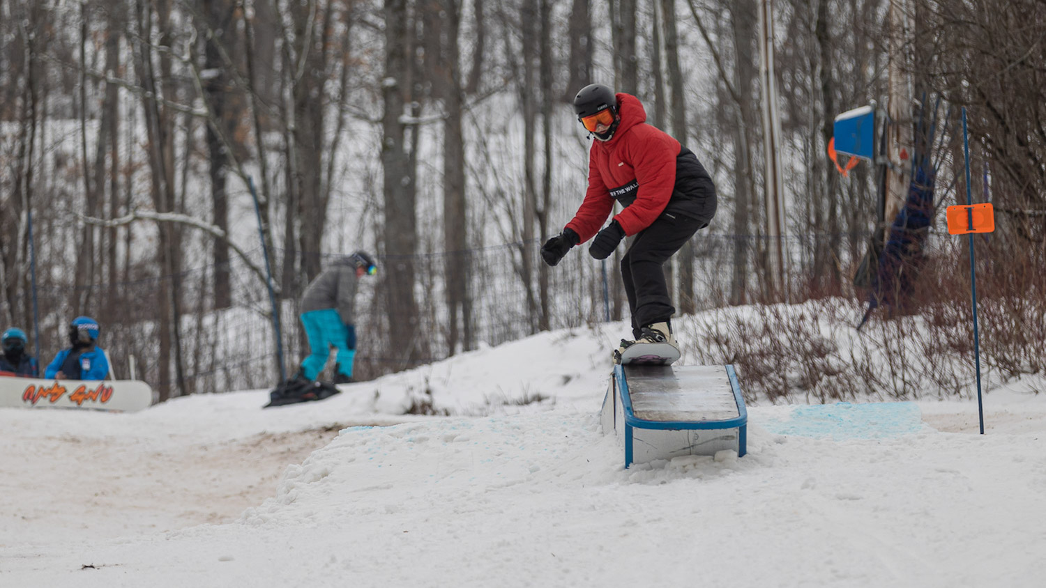 Snowboarder going down rail while Learning to snowboard in the park at Blue Mountain