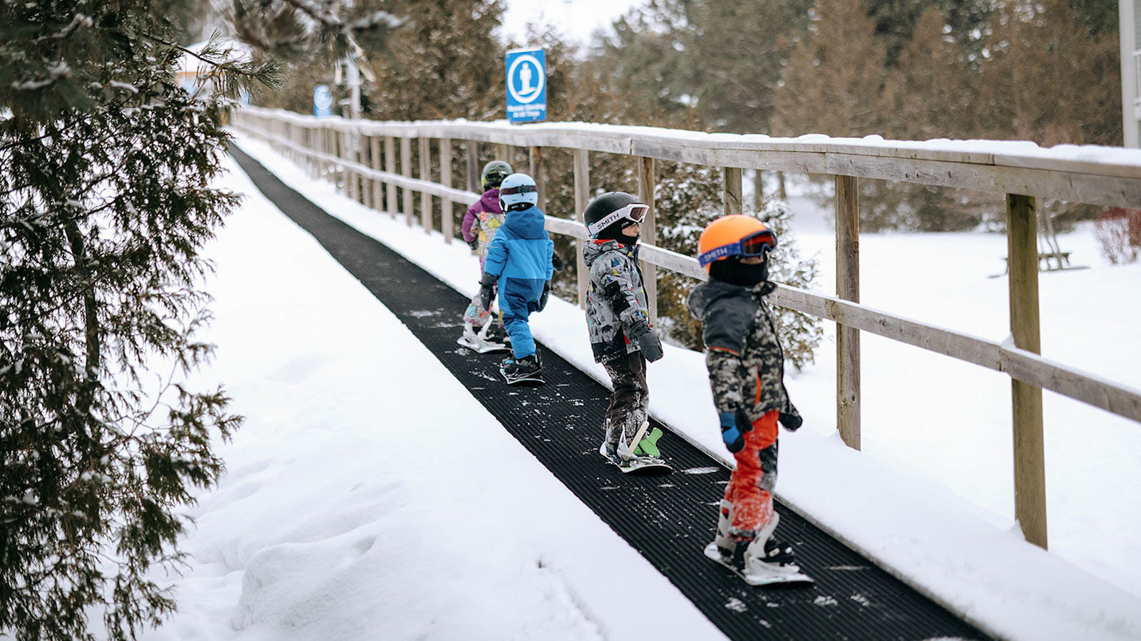 Small children going up Magic Carpet at Kids Group Snowboard Lesson Blue Mountain