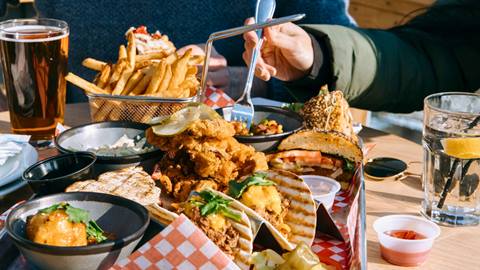 A person with fork, with a lot of food on the table at Rustys