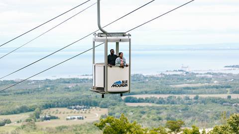 A couple enjoys a scenic view from a blue mountain cable car.