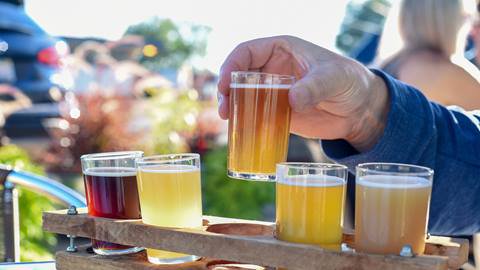 Man sampling a variety of seasonal craft beer at an outdoor beer garden, hands only