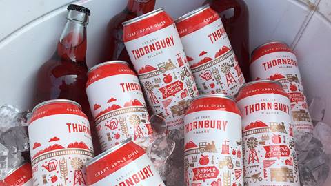 Bottles and cans of thornbury village craft apple cider chilled in a container filled with ice.