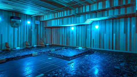 An empty sauna room illuminated with blue light.