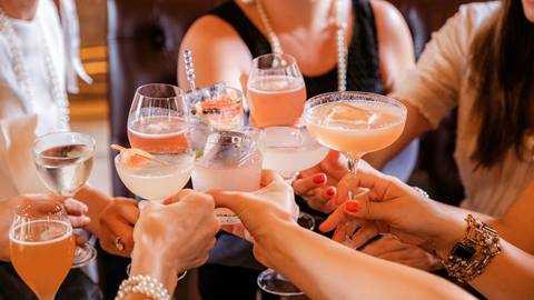 Group of people toasting with various cocktails.