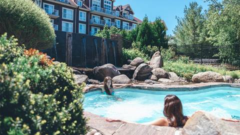 Two individuals relaxing by the side of a swimming pool on a sunny day.