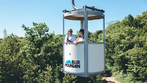 2 people riding the open air gondola at Blue Mountain Resort