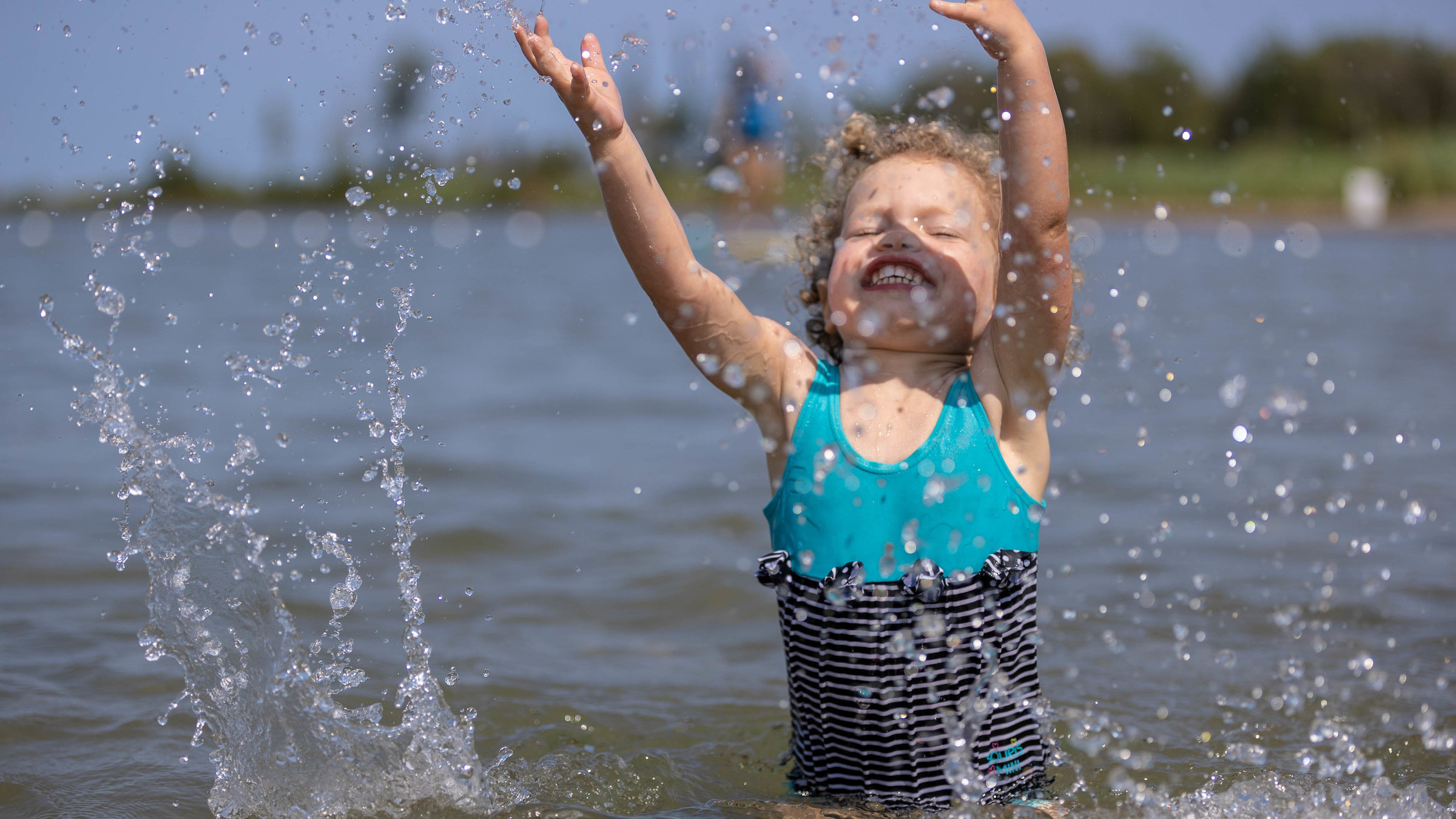 Child splashing in the water in Georgian Bay at Blue Mountain Beach