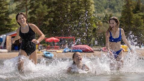 Group of people running into the water in Georgian Bay at the Blue Mountain Beach