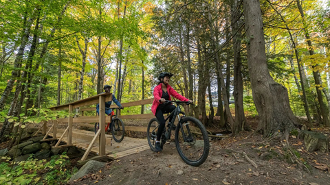 Two people riding bikes over a bridge and along a trail on the Blue Mountain Biking trails