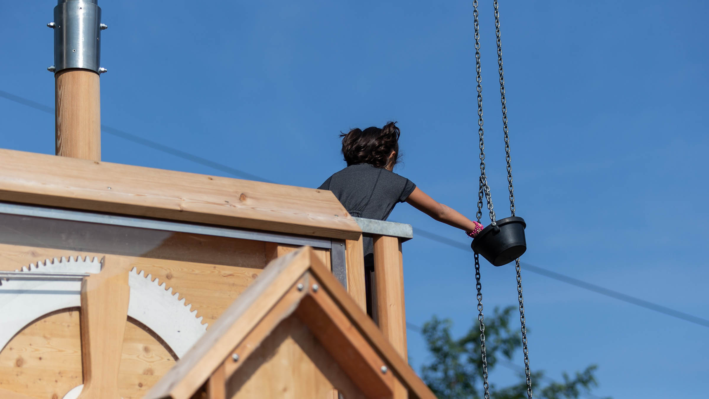 Child grabbing bucket with ball on Chutes & Loops Play Structure at Blue Mountain
