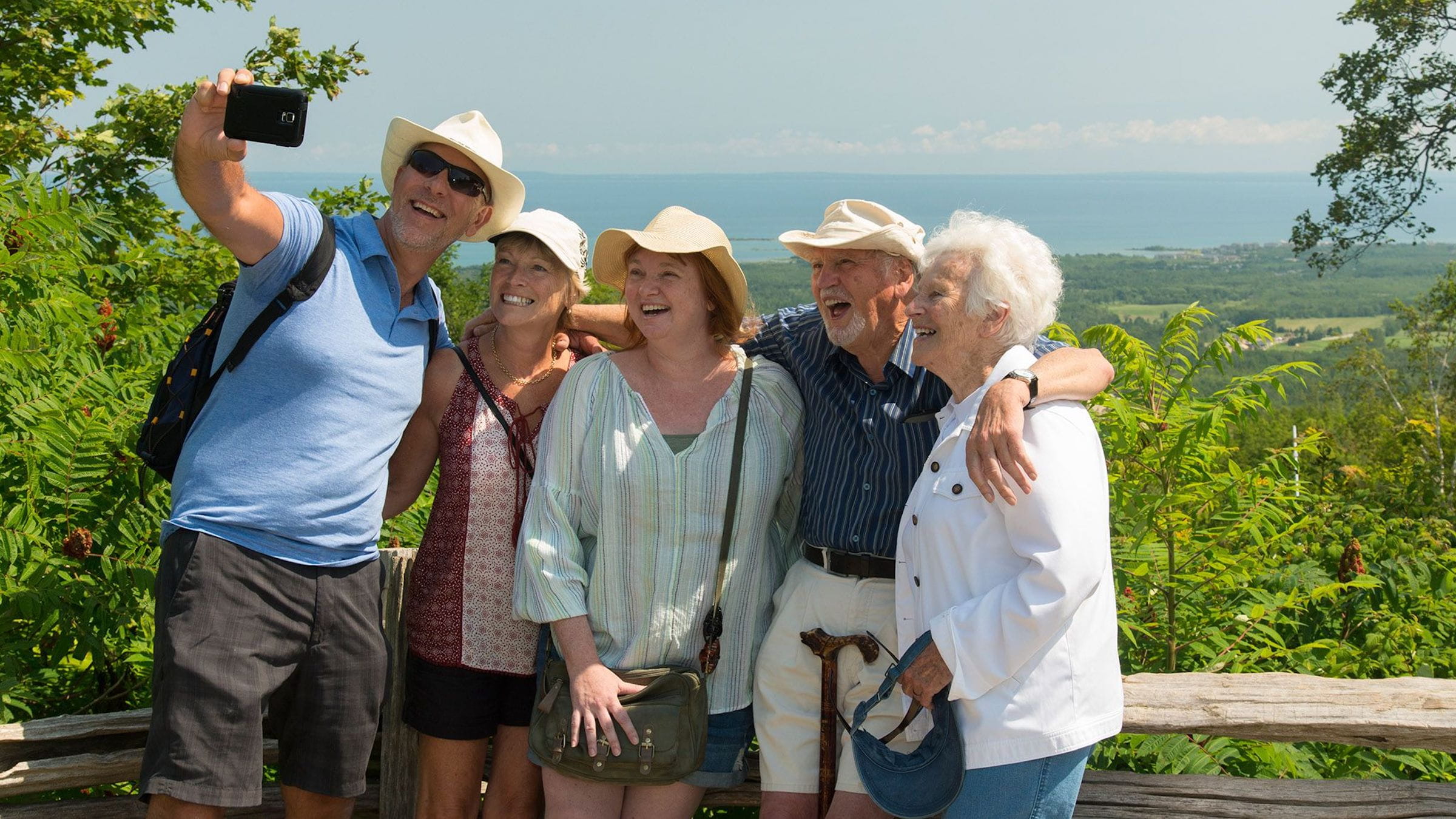 Group of family taking a selfie overlooking Georgian Bay at the top of Blue Mountain