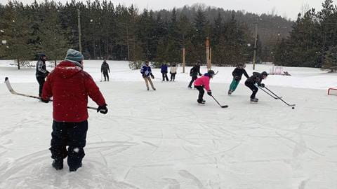 Group of friends playing shinny on outdoor ice hockey rink on the Niagara Escarpment at Blue Mountain Resort