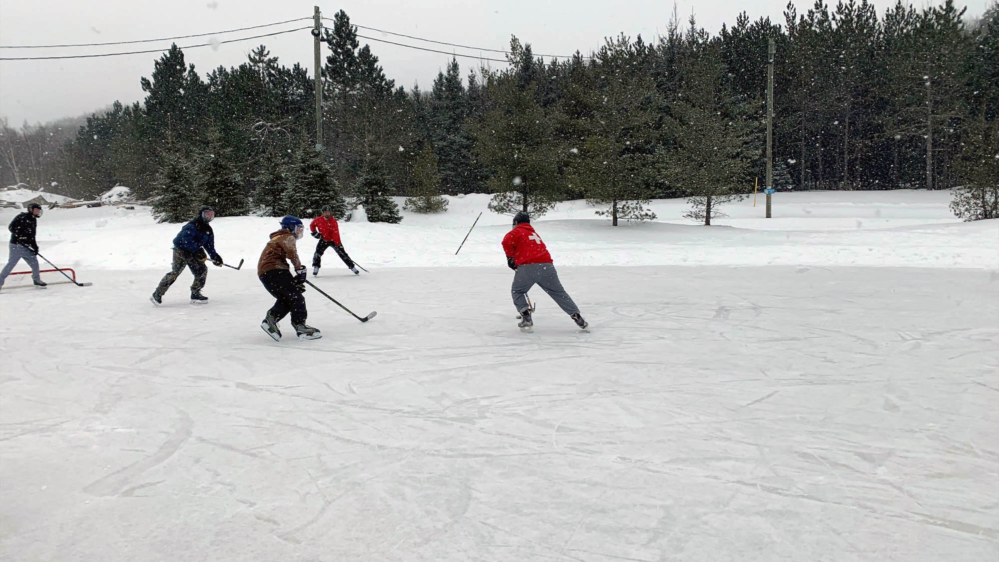 Group of friends playing shinny on outdoor ice hockey rink on the Niagara Escarpment at Blue Mountain Resort