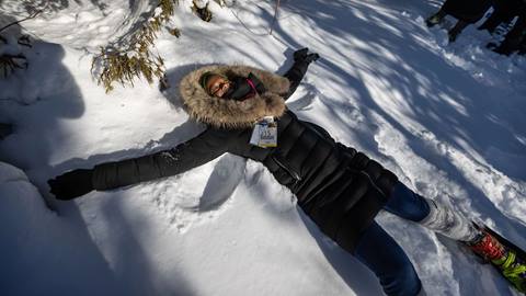 Woman lying in snow on Snowshoe trail at Blue Mountain resort 