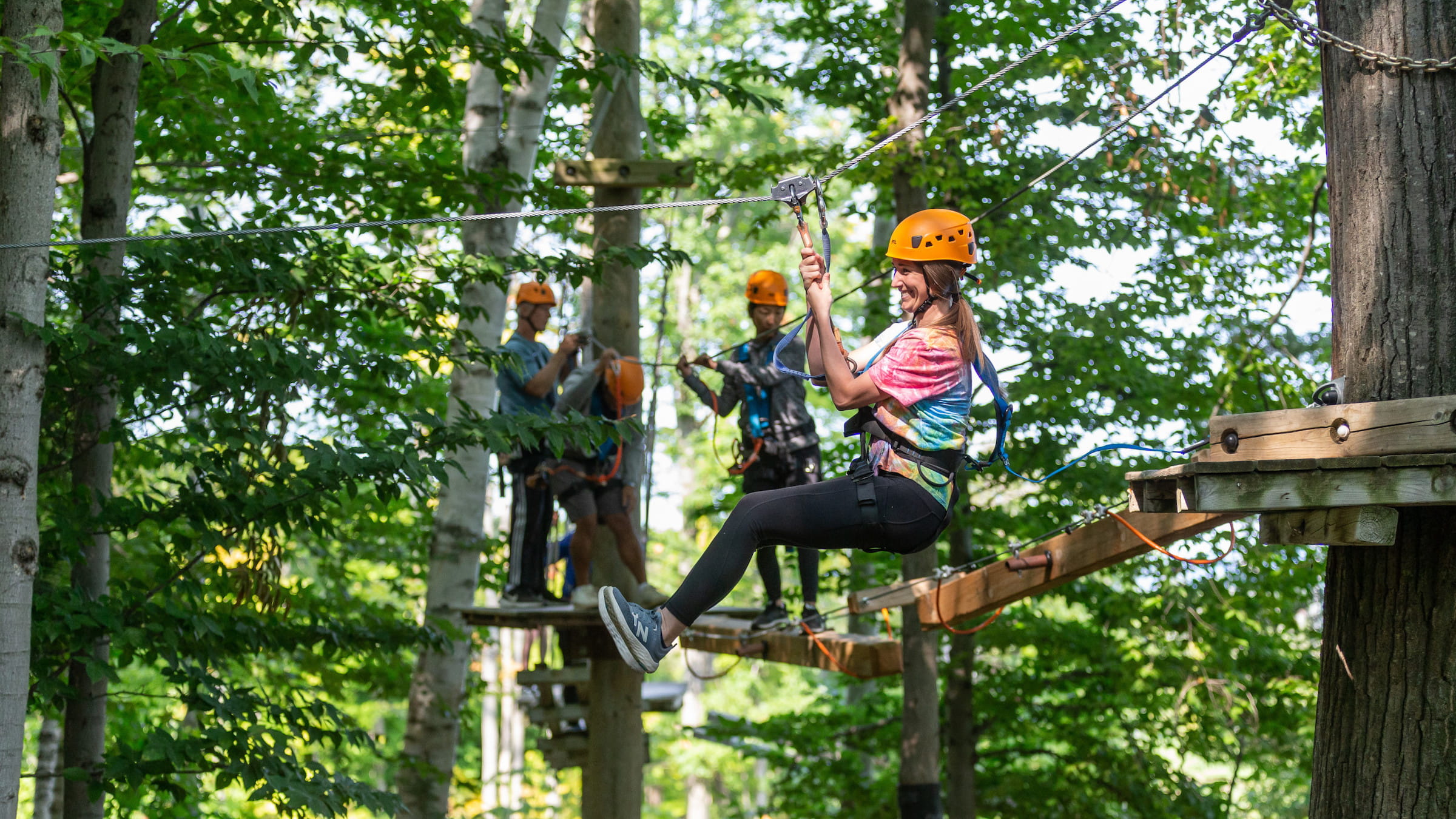 Group of people navigating the Timber Challenge High Ropes Course with a small zip line
