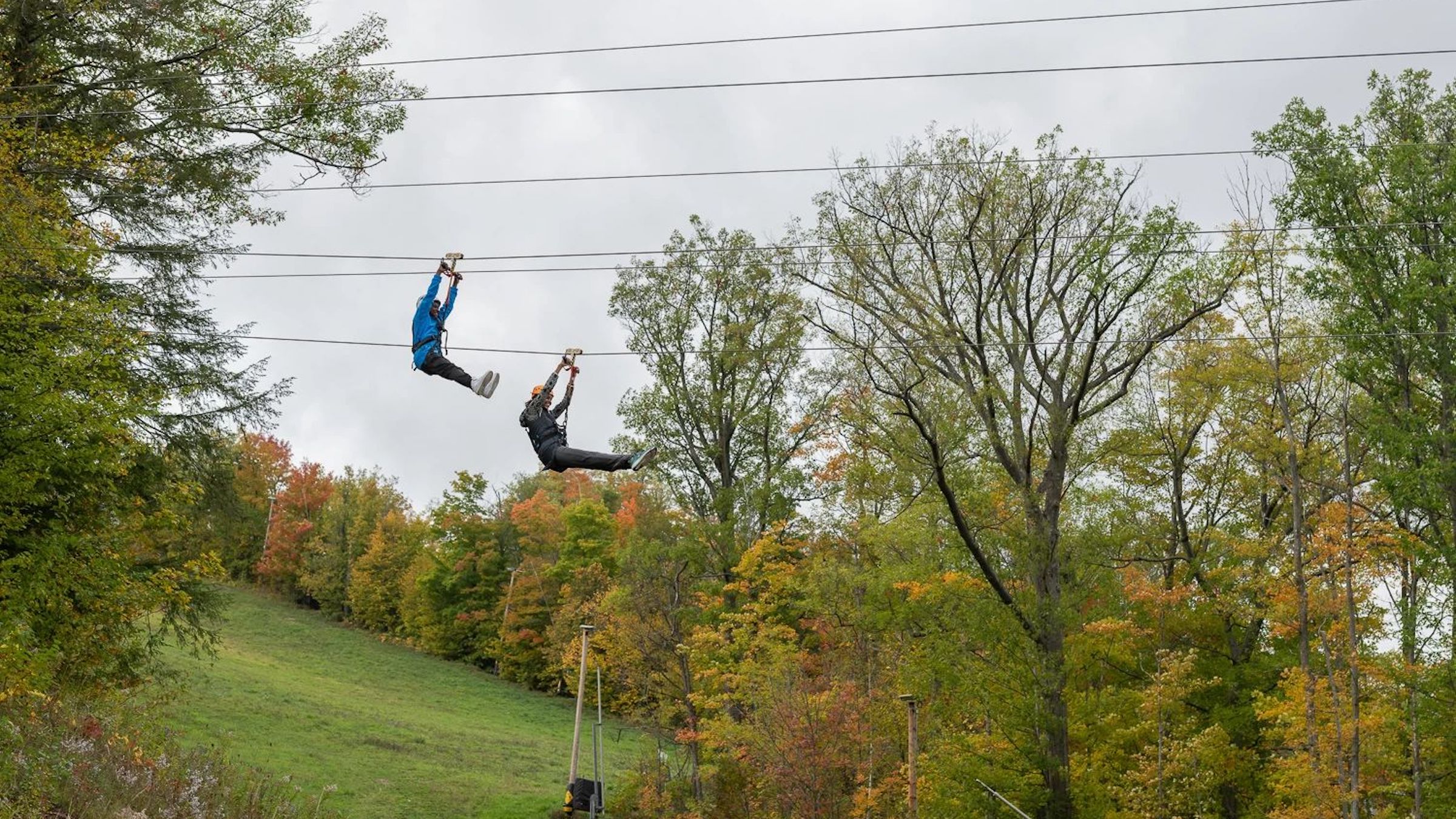 Two Blue Mountain Zipliners riding down Wind River Triple Zips Ziplining