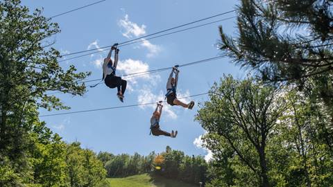 Three people riding down the ziplines on Blue Mountain's Wind Rider Triple Zips