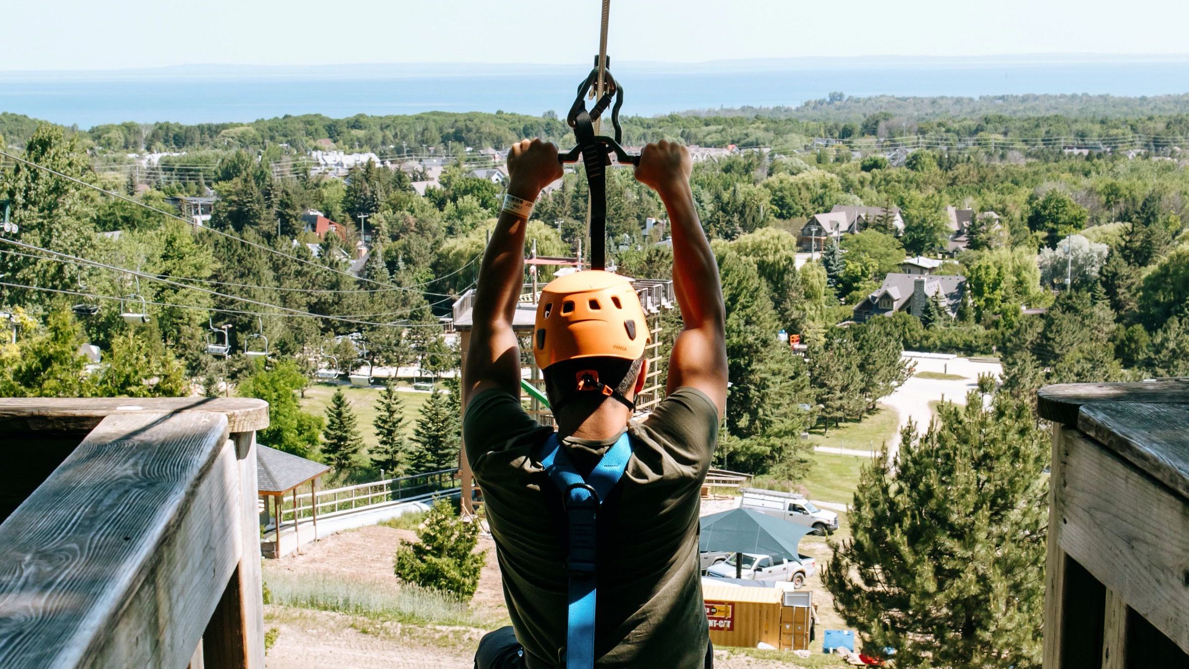 Person ziplining down Wind Rider Triple Zips at Blue Mountain with Georgian Bay in background