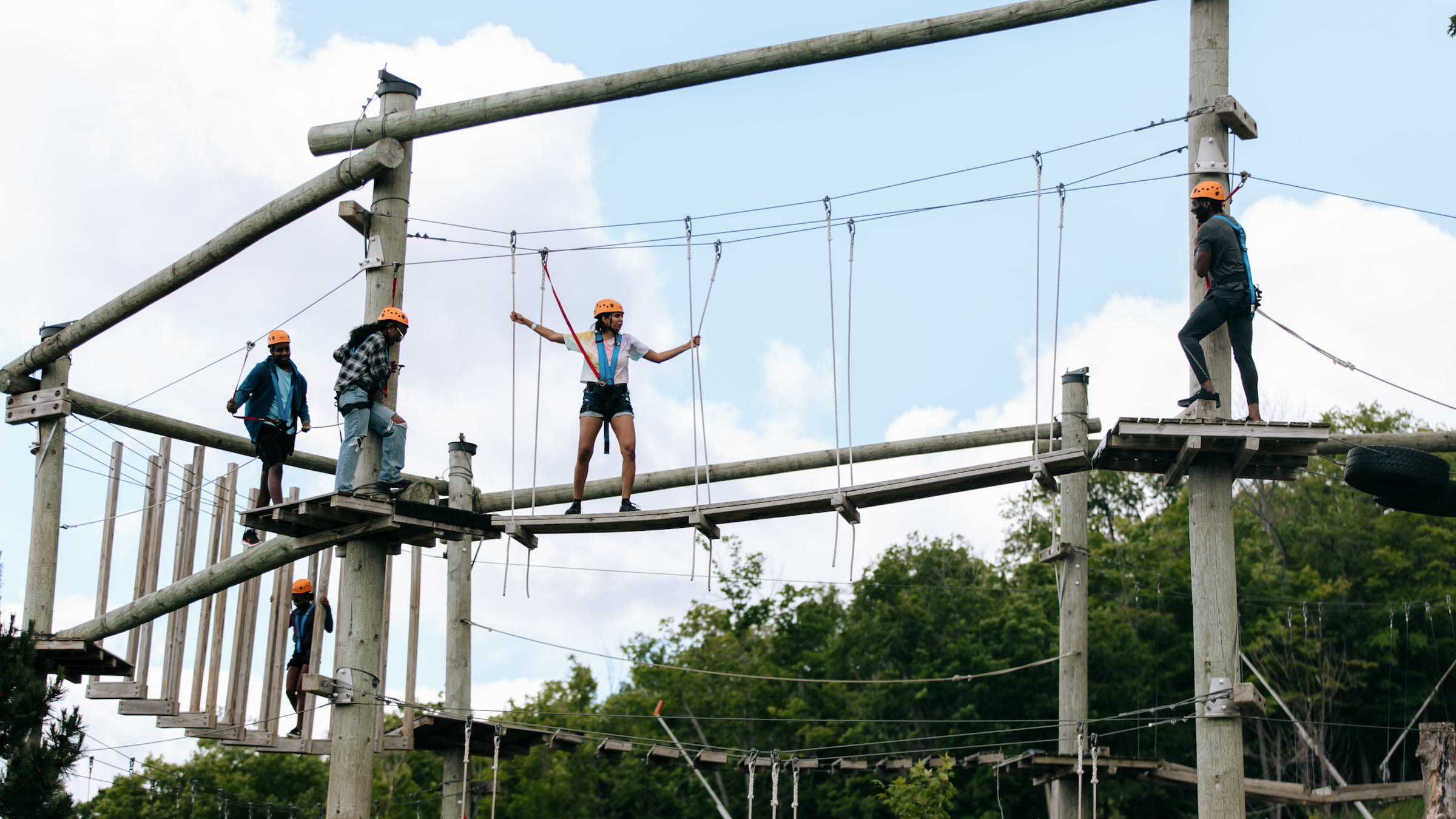 Group of friends navigating the low ropes on Woodlot Attraction at Blue Mountain