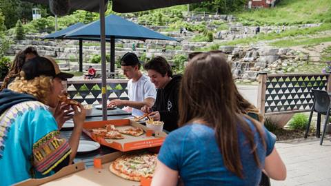 Group of friends eating pizza on the patio outside Grand Central Lodge in the summer at Blue Mountain
