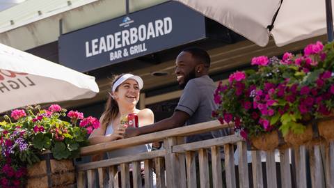 man and women hangout outside of leaderboard bar and grill.