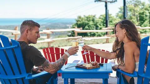 man and women sitting in muskoka chairs with drinks