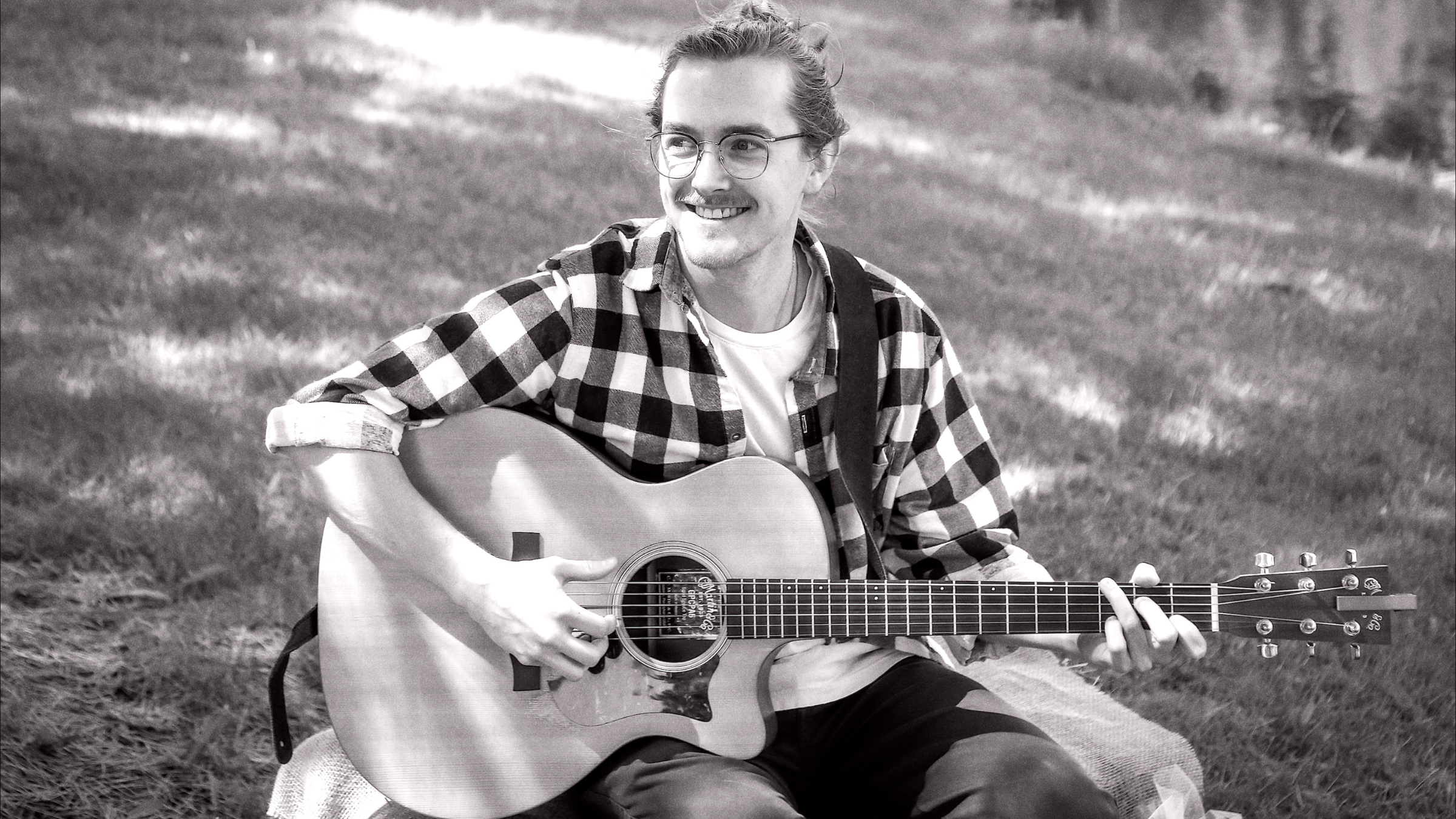 Alex Barber sitting outside with guitar