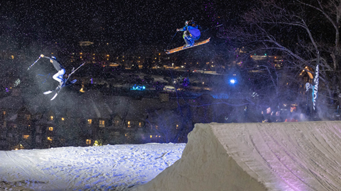 A skier doing a trick on a ramp at night.