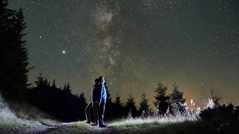 Two people standing on a trail looking up at the milky.