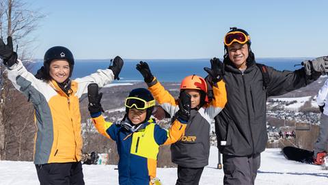 A family on the hill with their hands in the air