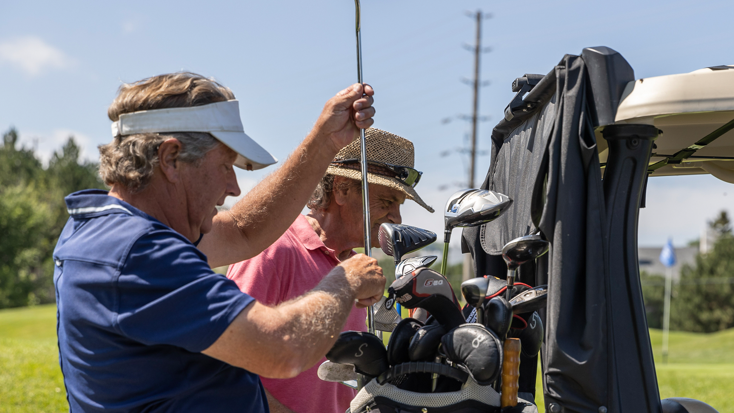 Golfers grabbing clubs out of their bags