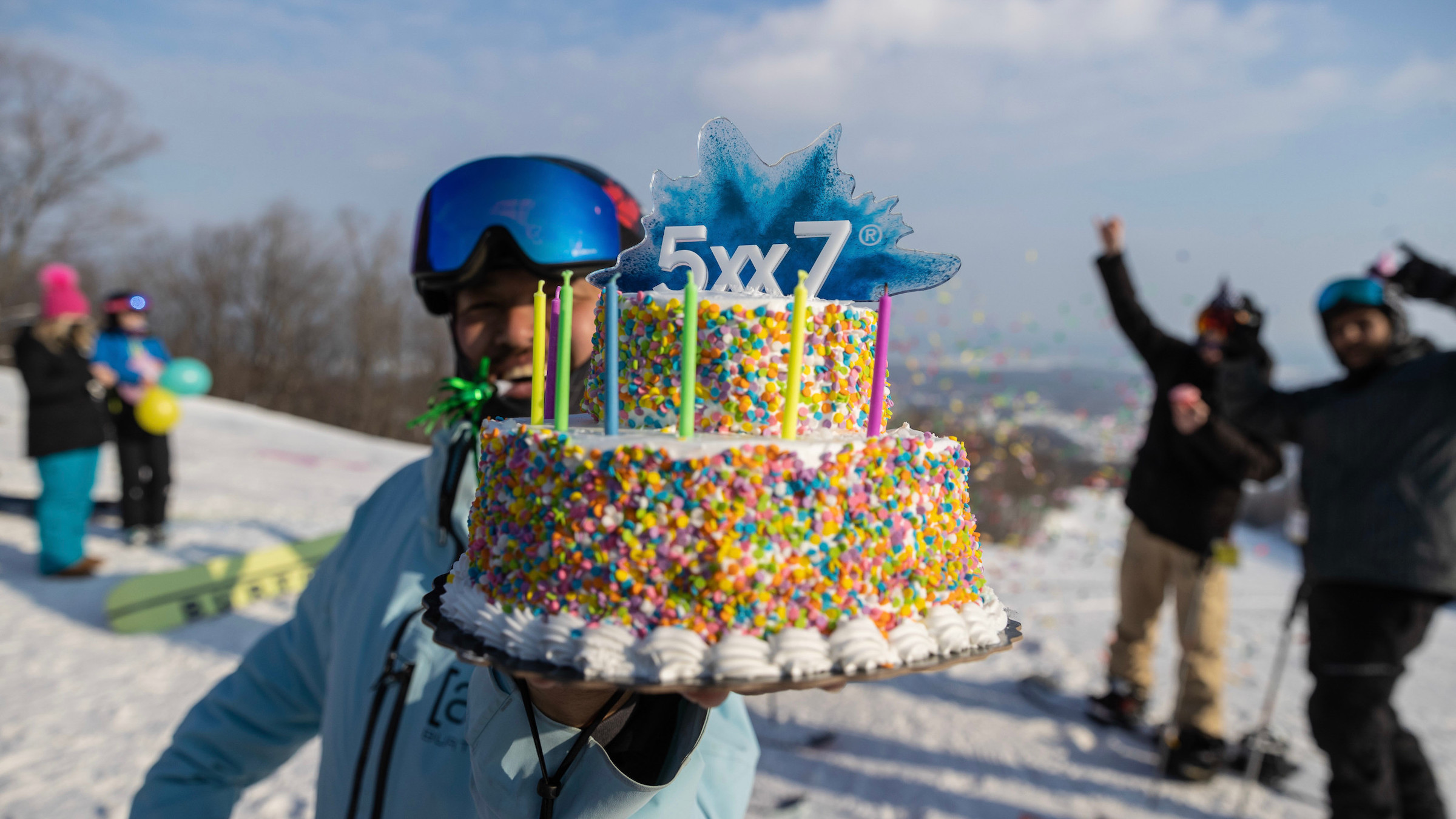 Man standing with 5x7 cake on blue mountain hill