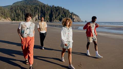 four people walking on the beach
