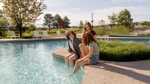 a group of people sitting on the edge of the pool