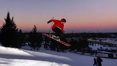 a man flying through the air while riding a snowboard down a hill