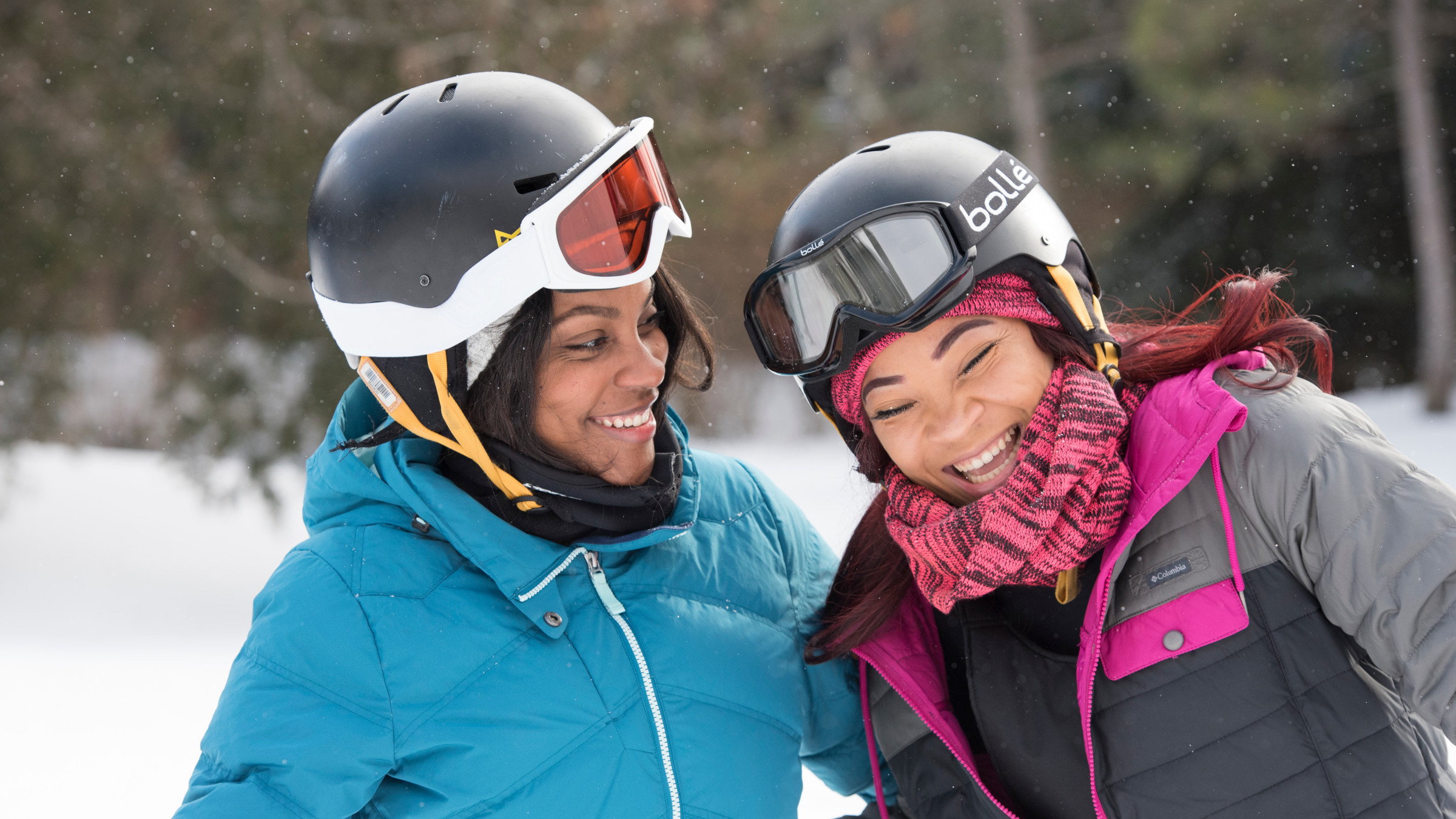 Two women in ski helmet and goggles laughing