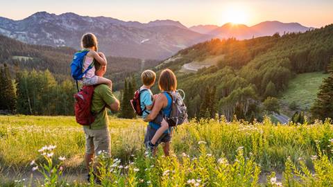 Family standing in a grass field taking in the view from their hike